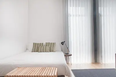 a white bedroom with a bed and a table at Citybreak-apartments Coliseu in Porto