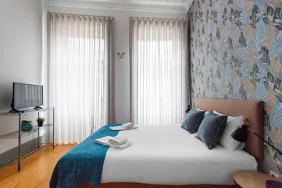 a bedroom with a large white bed and a television at Citybreak-apartments Coliseu in Porto