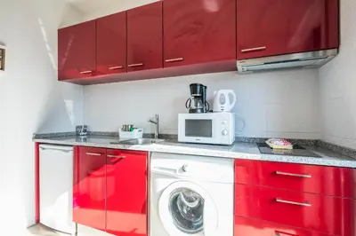 a kitchen with red cabinets and a washing machine at Apartamento À Francos Balcony in Porto