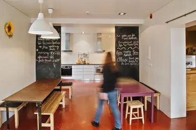 a woman walking in a kitchen with a table at Porto Spot Hostel in Porto