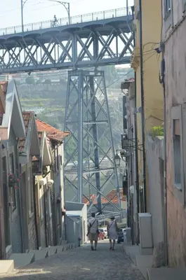 two people walking down a street with a bridge in the background at Modern and Cozy Apartment in Vila Nova de Gaia