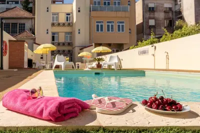 a table with two glasses of juice next to a swimming pool at 733 Costa Cabral Metro Residence in Porto