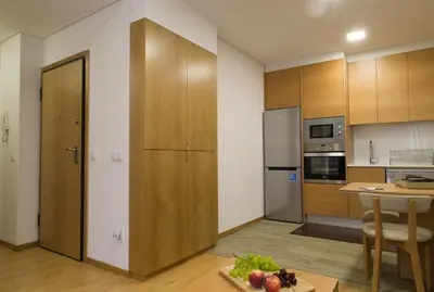 a kitchen with wooden cabinets and a table with a bowl of fruit at Spot Apartments Trindade in Porto
