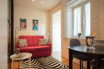 a living room with a red couch and a table at Modern loft w AC Downtown and Metro in Porto