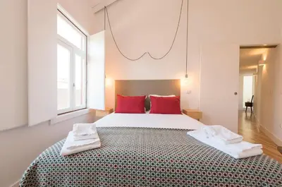 a bedroom with a large bed with red pillows at LovelyStay - Top Floor Balcony Apartment in Porto