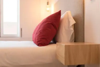 a red pillow and two white pillows on a bed at LovelyStay - Top Floor Balcony Apartment in Porto