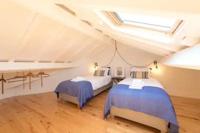 a attic bedroom with two beds and a skylight at LovelyStay - Top Floor Balcony Apartment in Porto