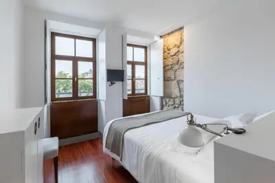 a white bedroom with a bed and a window at Goabio apartments 2 river view in Porto