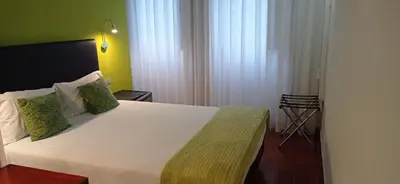 a bedroom with a large bed with a red wall at Hotel Paulista in Porto