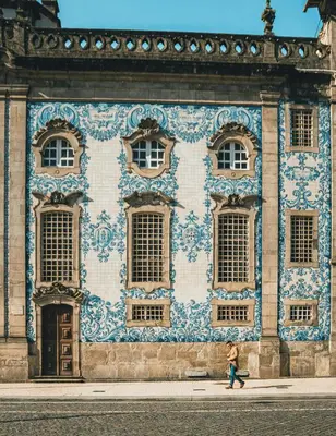 a woman walking past a building with blue and white tiles at Premium Apartment with Private Terrace & Garage in Porto