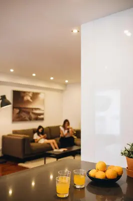 two people sitting on the couch in a living room with orange juice at Premium Apartment with Private Terrace & Garage in Porto