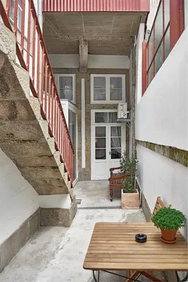 a porch with a wooden table and a stair case at PortoSense Almada in Porto