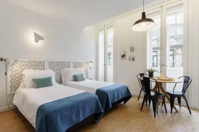 a hotel room with two beds and a table and a table and chairs at Galerias Nightlife Fashion Flats in Porto