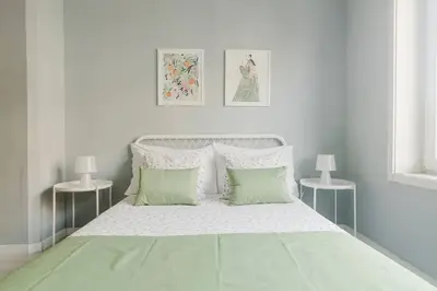 a white bedroom with a white bed with two tables at Lima House in Porto