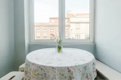 a table in a window with a vase with flowers on it at Lima House in Porto