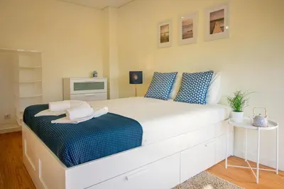 a bedroom with a large white bed with blue pillows at Green Suite in Porto