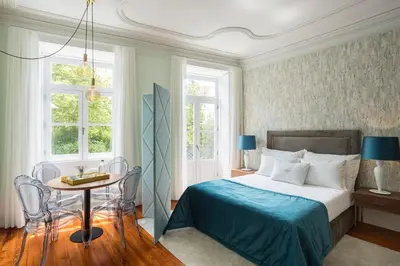 a bedroom with a bed and a table and windows at Predicados do Douro Palace in Porto