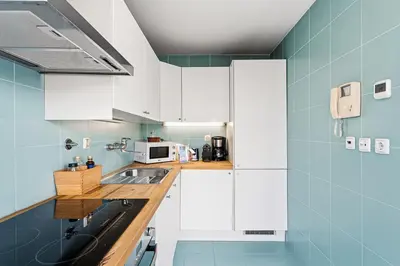 a kitchen with white cabinets and blue walls at GuestReady - Cosy studio in the heart of Porto in Porto