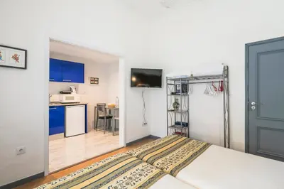 a bedroom with a bed and a kitchen with blue cabinets at Apartamento Garden Avenue in Porto