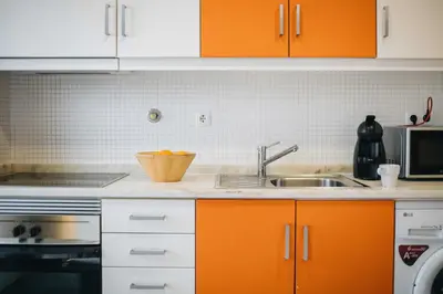 a kitchen with orange cabinets and a sink at Budget-Friendly Studio with Balcony in Rosario in Porto