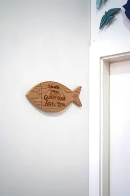 a wooden fish sign hanging on a white wall at The Blue and White Porto House in Porto