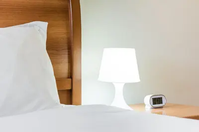 a bed with a lamp and a clock on a table at GuestReady - Sound of Nature - T1 Boavista in Porto