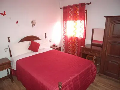 a bedroom with a bed with a red blanket and a window at Pensão França in Porto