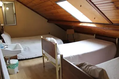 a bedroom with two beds and a sink and a skylight at Pensão França in Porto