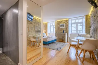 a living room with a table and a bedroom at PWHC Miragaia Apartments in Porto