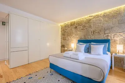 a bedroom with a large bed and a stone wall at PWHC Miragaia Apartments in Porto