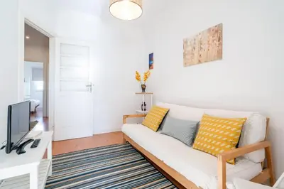 a living room with a white couch and a tv at Covelo Park Apartment in Porto