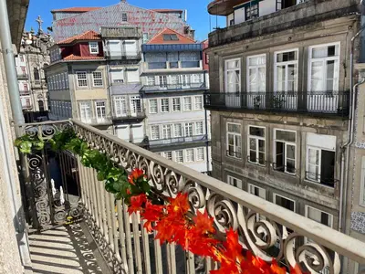 a balcony with a bunch of red flowers on it at Ribeira Historic Apartments in Porto