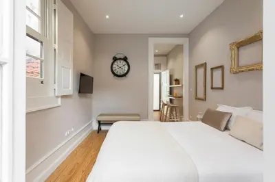 a bedroom with a bed and a clock on the wall at Ribeira Historic Apartments in Porto
