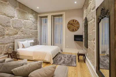 a bedroom with a bed and a stone wall at Ribeira Historic Apartments in Porto