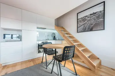 a room with a table and chairs and a staircase at Sá de Noronha Mezzanine w Terrace in Porto