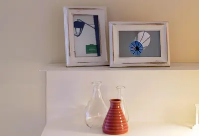 two glass vases sitting on a shelf with two frames at HM - Pinheiro Cosy Apartment in Porto
