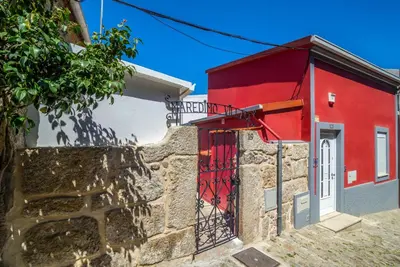 a red building next to a stone wall with a gate at Maredimo Village Porto Casa 1 in Porto