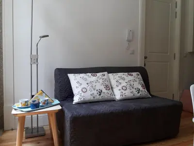 a couch with two pillows on it with a table at Oporto Cosy Apartment at Alegria in Porto
