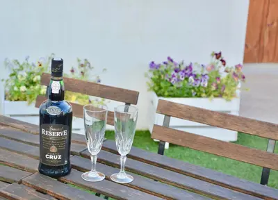 a bottle of wine and two glasses on a wooden bench at Porto Garden Villas | Downtown in Vila Nova de Gaia