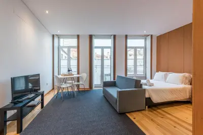 a bedroom with a bed and a chair and a television at GuestReady - Given to fly in Porto
