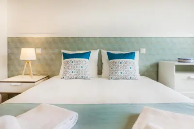 a bedroom with a large white bed with blue pillows at Camões Executive Flat in Porto