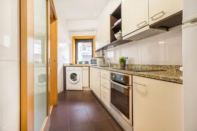 a kitchen with white cabinets and a washer and dryer at Camões Executive Flat in Porto