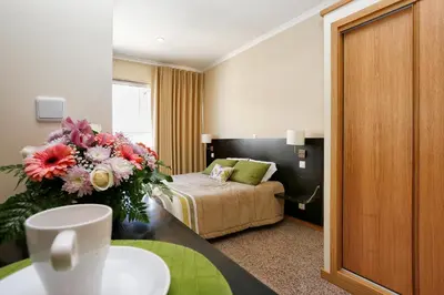 a hotel room with a bed and a vase of flowers at Oporto City Centre Apartments in Porto