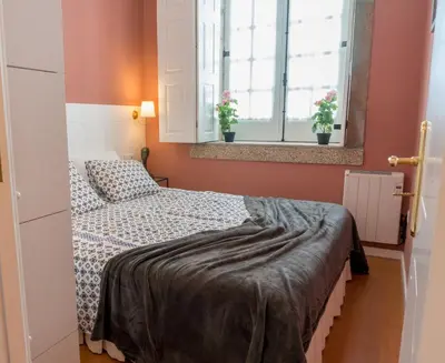 a small bedroom with a bed and two windows at Oporto Centre Clean & Cozy Apt 2 in Porto