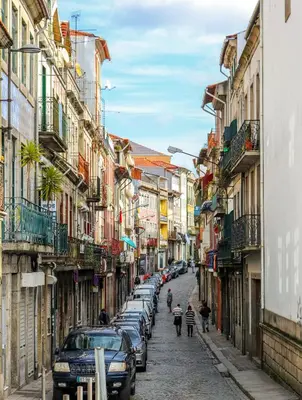 a city street with parked cars and people walking down the street at Bluetile Sol Apartment in Porto