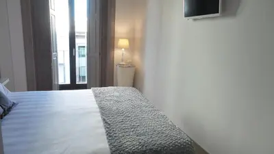 a bedroom with a bed with a television and a window at Porto Tropical Charm in Porto