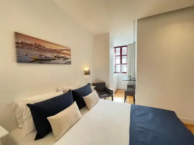 a small kitchen with white cabinets and a window at MyStay Porto Centro in Porto