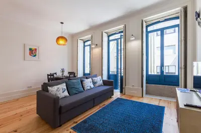 a living room with a couch and some windows at Home Alegria in Porto