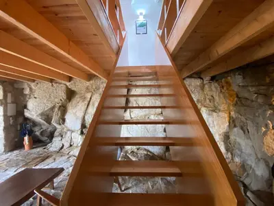 a wooden staircase in a room with a stone wall at Casa Dona Olga River View in Porto