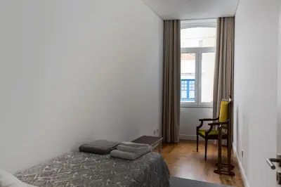 a bedroom with a bed and a chair and a window at Casa Velha Guesthouse in Porto